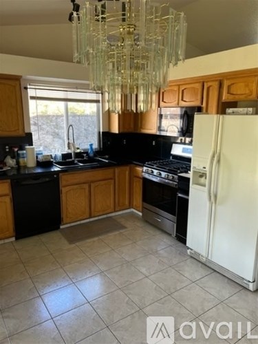 A kitchen with a white refrigerator and a chandelier hanging from the ceiling.