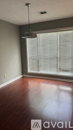 A room with wooden floors and a window with blinds.