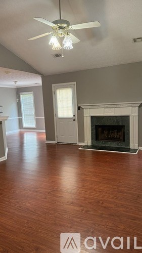 A living room with a fireplace and a ceiling fan.