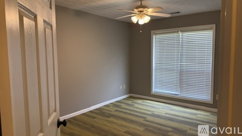 A room with a ceiling fan and a window with blinds.