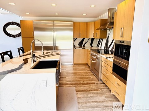 A modern kitchen with wooden cabinets and a marble countertop.