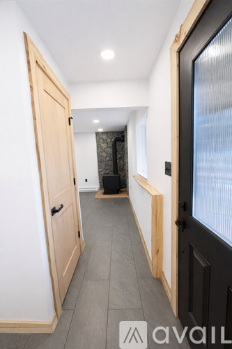 A hallway with a wooden door on the left and a black door on the right.
