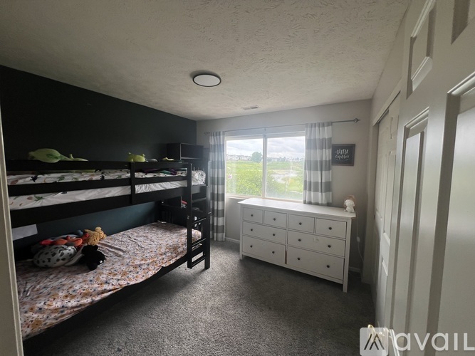 A bedroom with bunk beds and a dresser with a window.