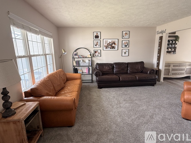 A living room with a brown leather couch and an orange couch.