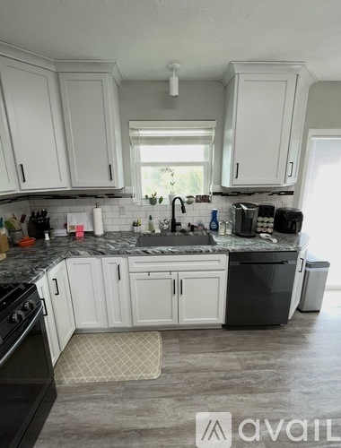 A kitchen with white cabinets and a black stove top oven.