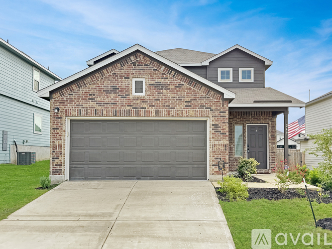 A brick house with a grey garage door is for sale.