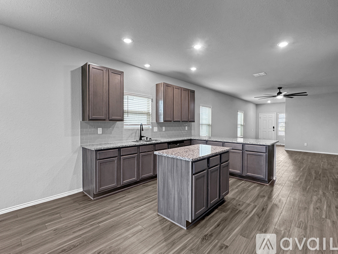 A modern kitchen with wooden cabinets and a marble island.
