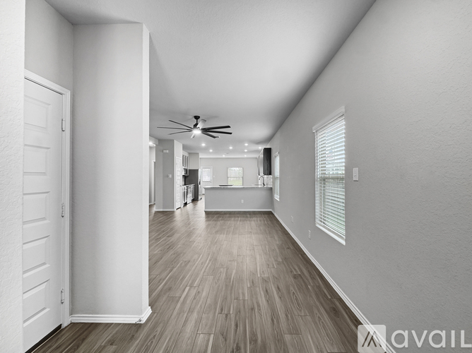 A spacious room with a ceiling fan and wooden flooring.