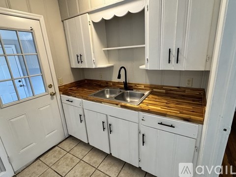 A kitchen with white cabinets and a wooden countertop.