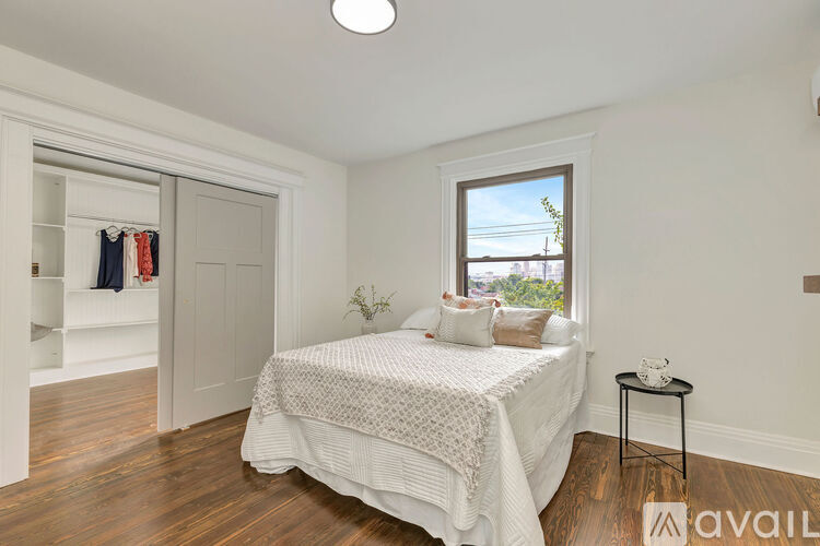 A bedroom with a bed, a small table, and a window.