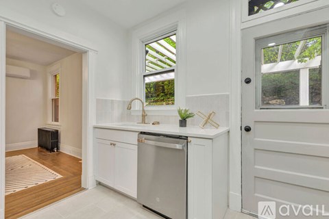 A kitchen with white cabinets and a window.