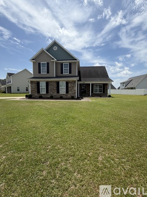 A house with a grey roof and a stone wall in front.