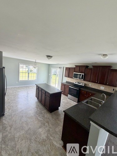A kitchen with dark brown cabinets and a black refrigerator.