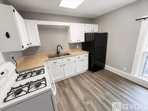 A kitchen with white cabinets and a black refrigerator.