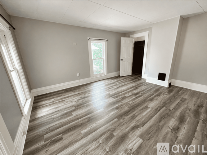 A spacious room with wooden flooring and white walls.