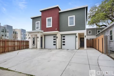 A modern two-story house with a red and grey exterior and a white garage door.