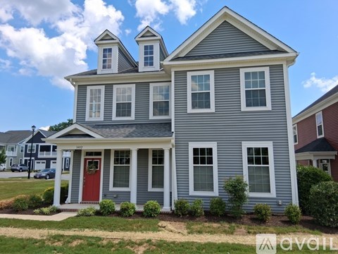 A two-story house with a red door and a grey exterior.