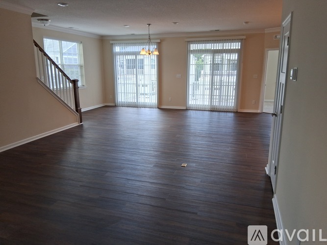A spacious living room with hardwood floors and a staircase on the left side.