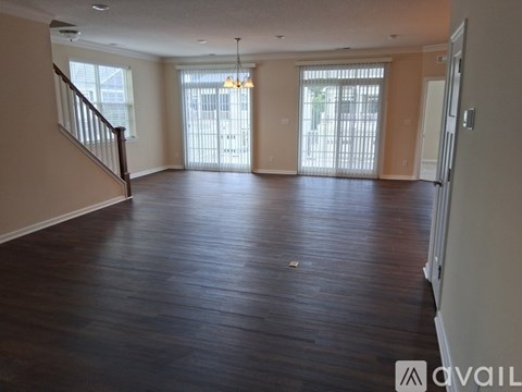 A spacious living room with hardwood floors and a staircase on the left side.