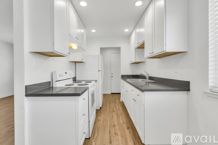 A modern kitchen with white cabinets and a wooden floor.