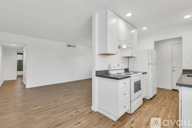 A kitchen with white appliances and wooden floors.