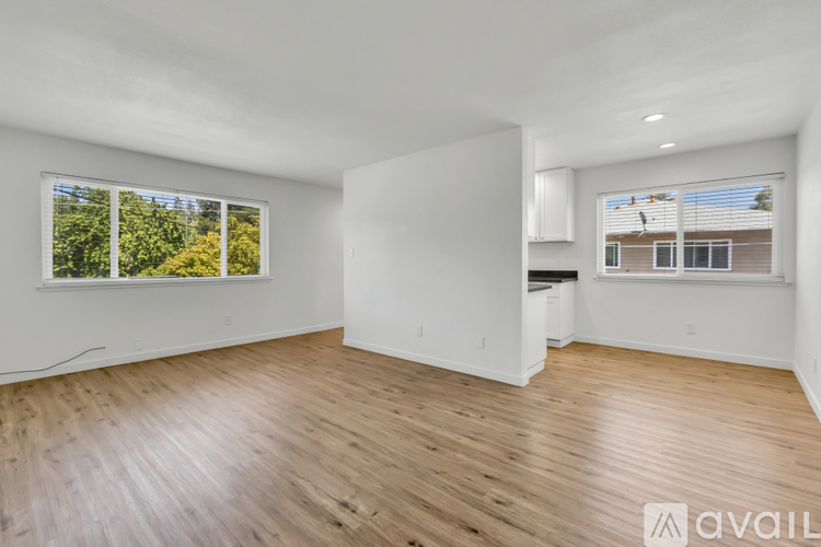 A spacious room with wooden flooring and large windows.