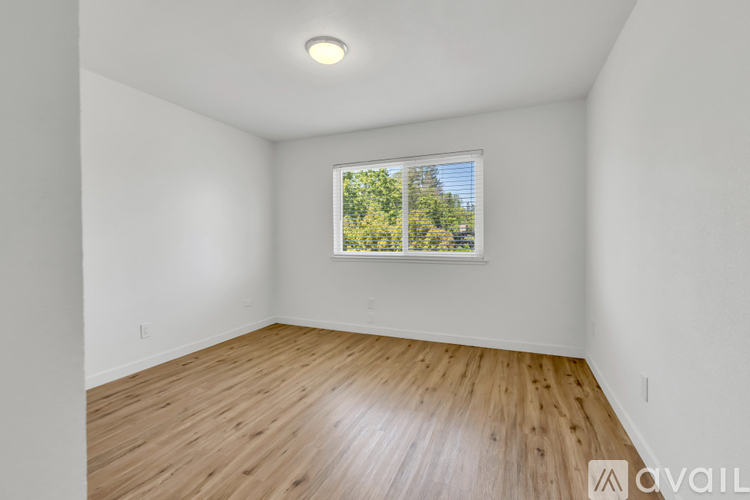 A room with wooden flooring and a window showing trees outside.