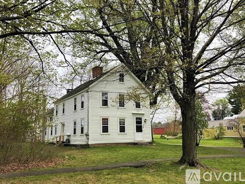A white house with a tree in front of it.