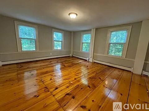 A room with wooden floors and three windows.