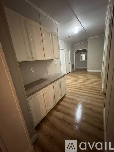 A long hallway with wooden floors and white walls.
