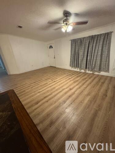 A room with wooden flooring and a ceiling fan.