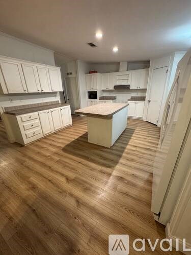 A kitchen with wooden floors and white cabinets.