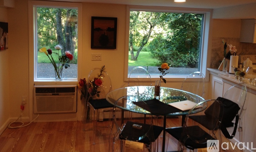 A dining room with a table and chairs and a vase of flowers.