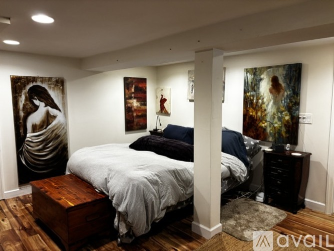 A bedroom with a large bed and two paintings on the wall.