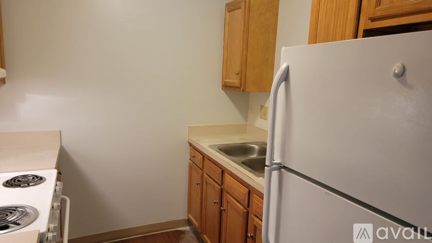 A kitchen with a white refrigerator, wooden cabinets, and a stove top.
