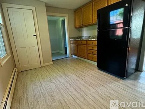A kitchen with a black fridge and wooden cabinets.