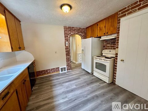 A kitchen with wooden cabinets and a brick wall.