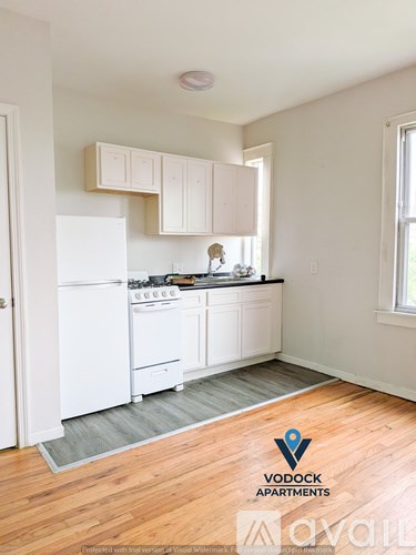 A kitchen with white appliances and wooden floors.