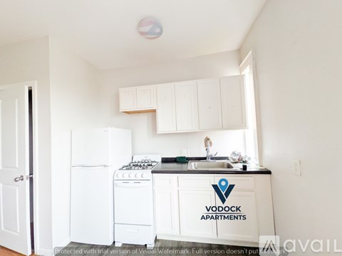 A Vodock Apartments kitchen with white appliances and cabinets.