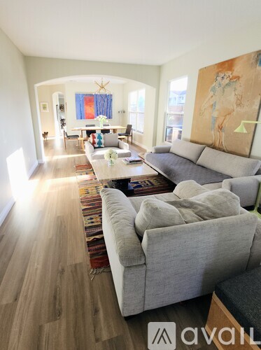 A living room with a grey couch and a painting on the wall.