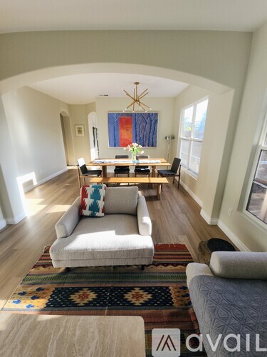 A living room with a white couch and a rug.