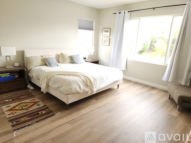 A bedroom with a large bed and a window with curtains.