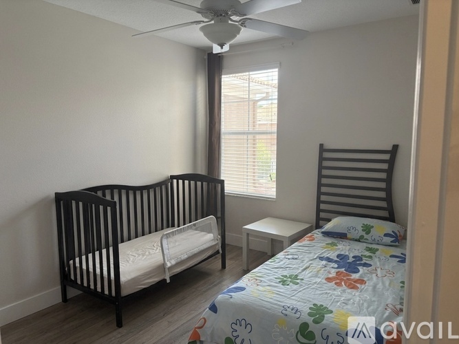 A bedroom with a crib and a bed with a floral bedspread.