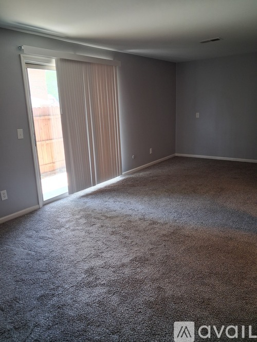 A room with carpeted floor and a sliding glass door.