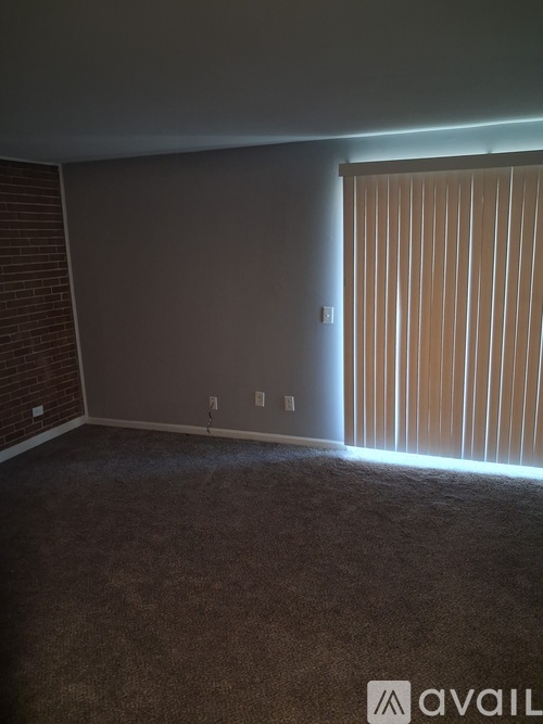 A room with a carpeted floor and a window with blinds.