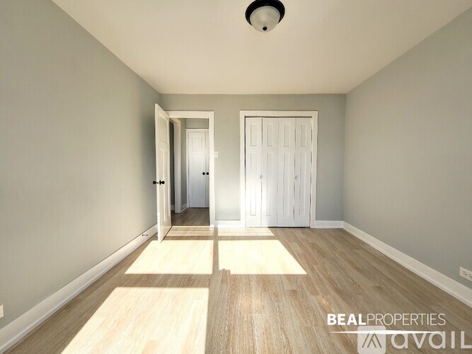 A spacious room with a wooden floor and two white doors.