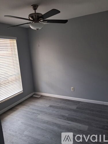 A room with a ceiling fan and a window with blinds.