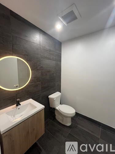 A bathroom with a toilet, sink and mirror.