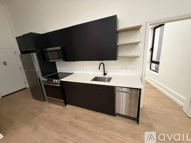 A kitchen with black cabinets and a white backsplash.
