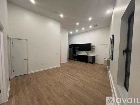 A spacious room with wooden flooring and white walls.